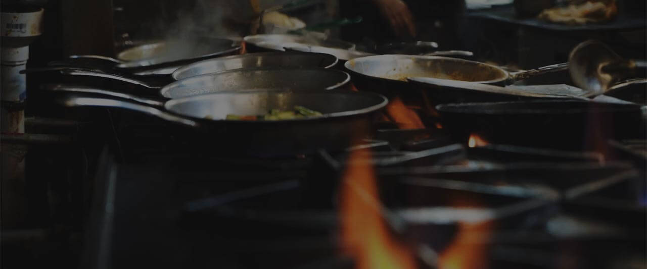Stylized orange image of commercial kitchen stove with several pans
