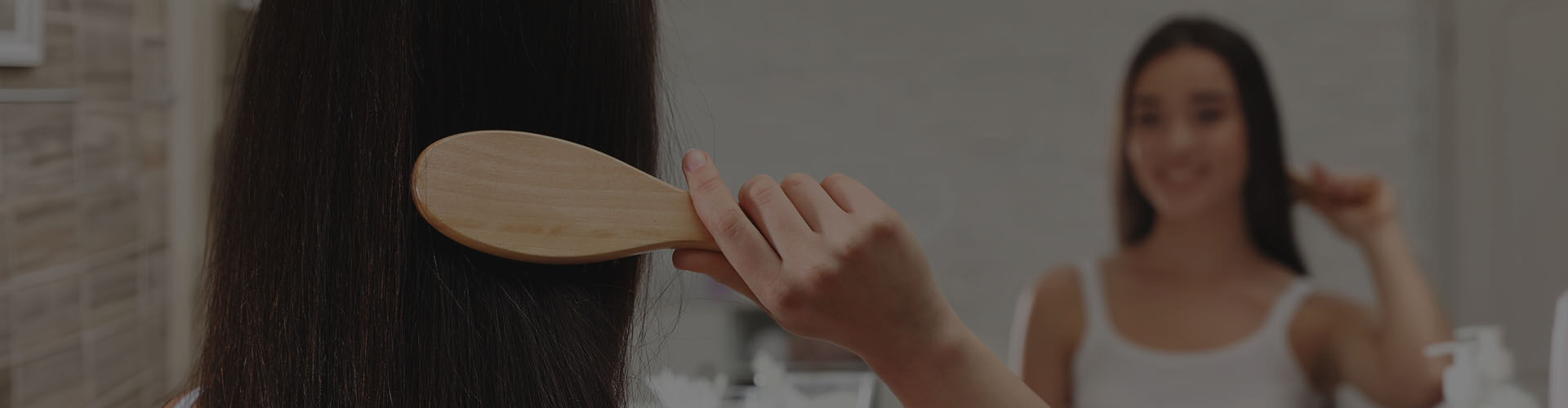 Image of woman brushing her hair in the mirror